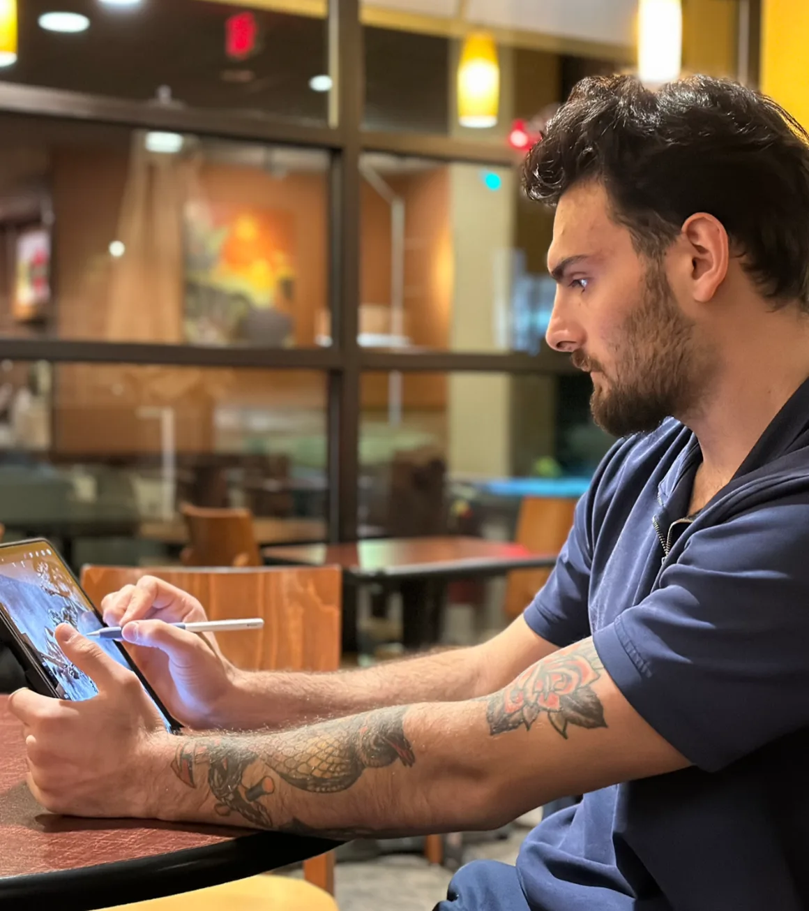 Nadir drawing on an iPad at a cafe table